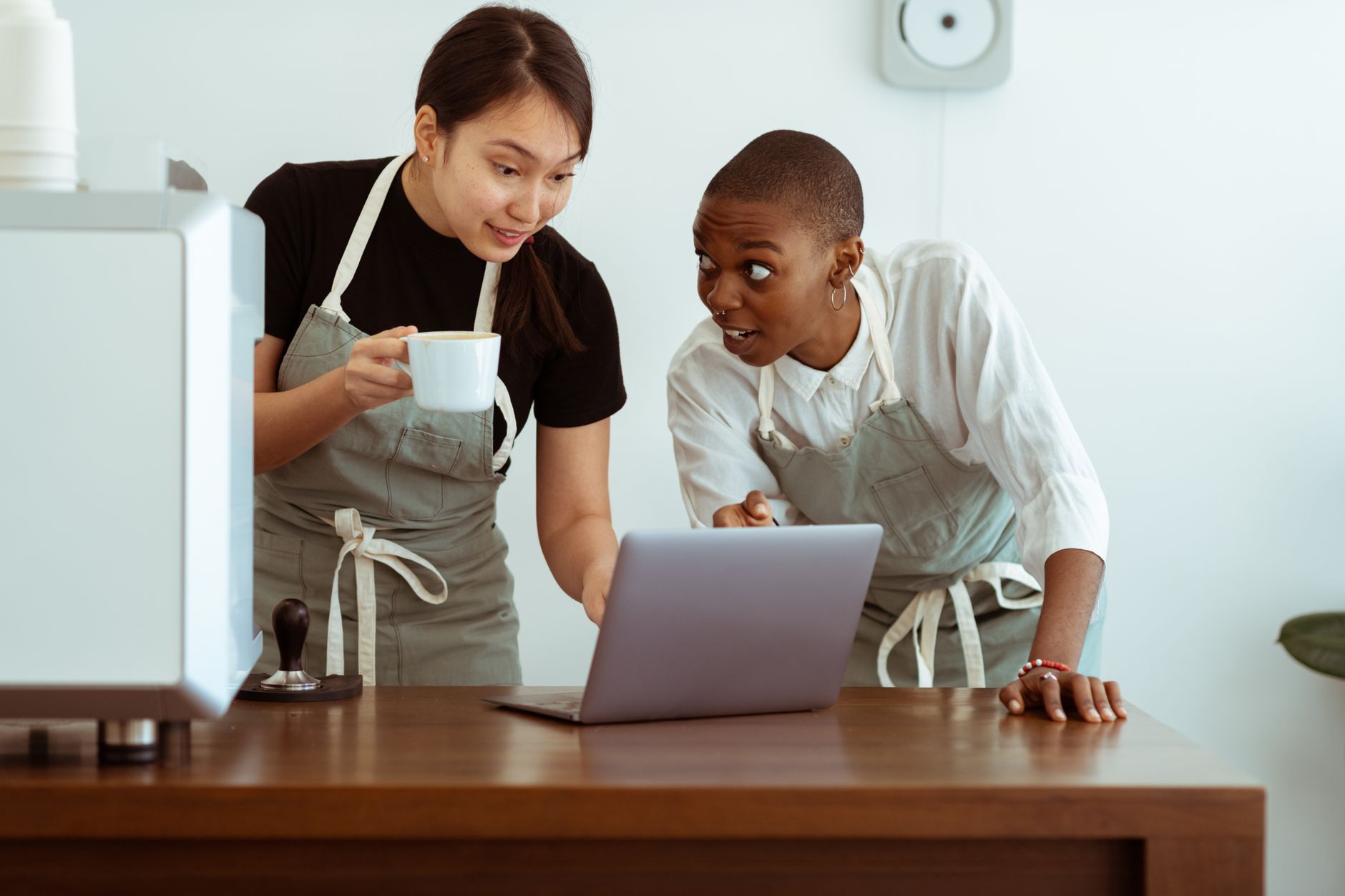 positive waitresses working on laptop and discussing work