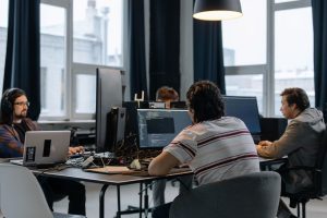 men sitting at the desks in an office and using computers