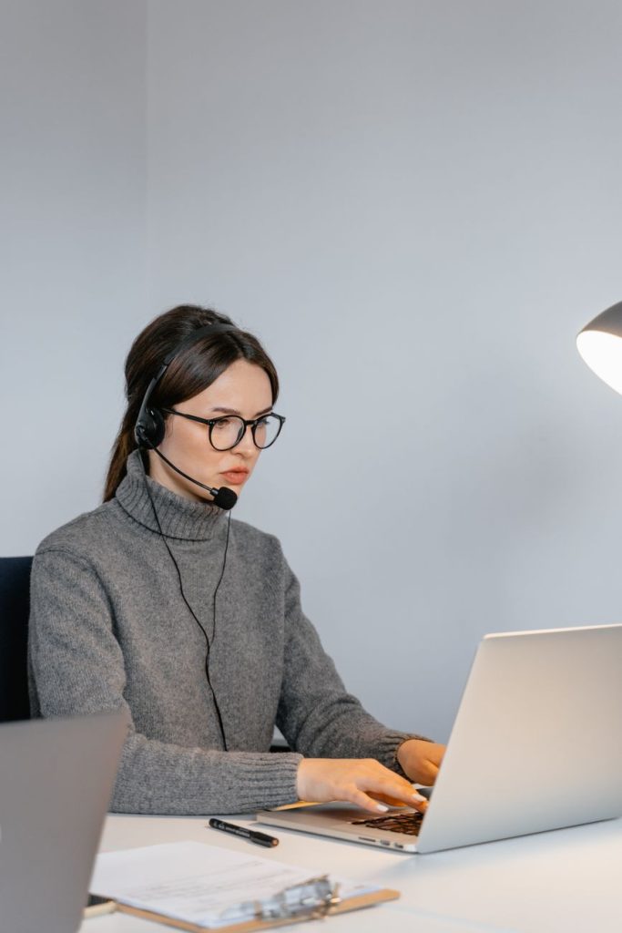 woman in a gray sweater typing on her laptop